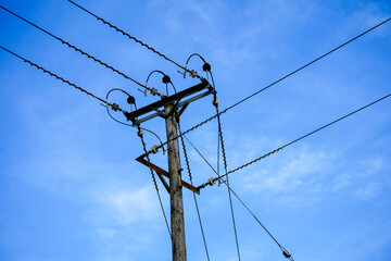 Looking up at power pylons with blue sky and clouds background