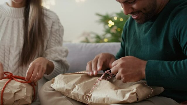 Multi ethnicity couple opening similar Christmas presents at home. Shot with RED helium camera in 8K.    