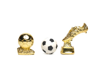 A picture of miniature golden boots, golden ball and football on white background. 