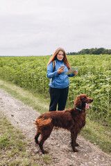 Woman with paper map, smart phone and her friend dog on country road background. Human and a dog....