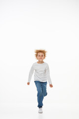 Full-length portrait of little girl, kid in white long sleeve blouse and jeans isolated over white background. Fashion, happy childhood