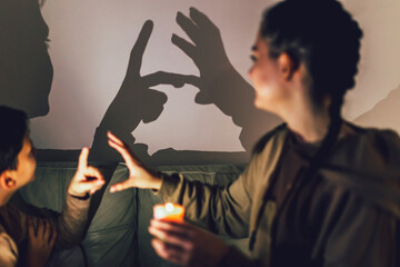 Brother and sister playing with shadows at home.