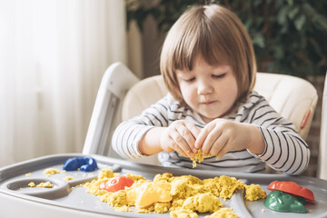 Cute little boy playing with kinetic sand. Development of fine motor skills. Early sensory education. Activities Montessori. Sensory plays at home.