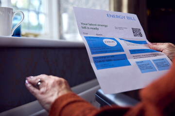 Close Up Of Senior Woman In Wheelchair With Energy Bill By Radiator In Cost Of Living Energy Crisis