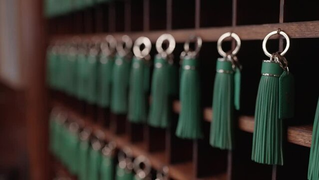 Hotel key rack made of mahogany with green tassels attached to each key.