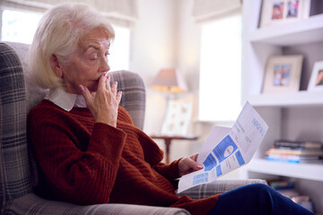 Worried Senior Woman At Home Looking At USA Energy Bill During Cost Of Living Energy Crisis