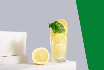 Zumo de limón con rodajas de limón y menta sobre fondo gris y verde	