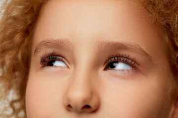 Closeup of little girl's eye with black curly eyelashes. Kids ophthalmology. Children female face with open eyes.
