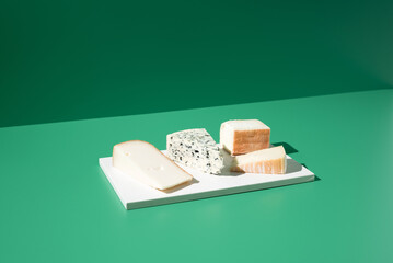 Surtido de quesos franceses. Queso de leche de cabra, vaca y oveja sobre un fondo verde	
