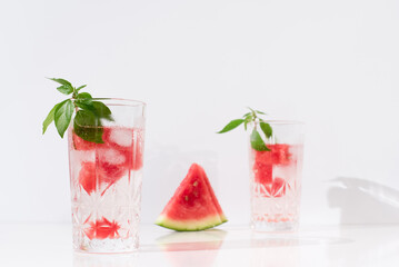 Dos vasos de zumo de sandía con trozos de sandia y hielo sobre fondo claro	