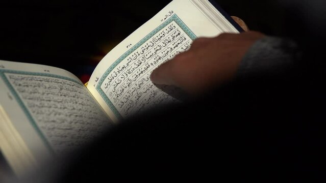 Reading Quran, Reading a Koran, Reading a Holy Quran with finger. Quranic reading. Reading a holy book. reading the Holy Qur'an, Reading in dark, Slowmotion Footage.