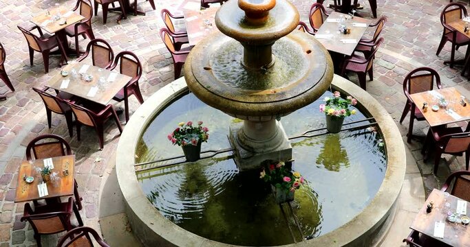 Empty Restaurant Tables Around The Old Round Stone Fountain On The Place Du Thouron In Seillans In The Var In France - DCi 4K Resolution
