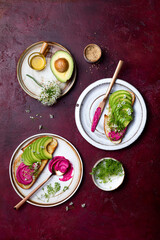 Obraz na płótnie Canvas Avocado toast with pink beet hummus spread or dip with edible onion flowers and microgreens. Healthy plant based appetizer, vegan, vegetarian snack