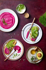 Avocado toast with pink beet hummus spread or dip with edible onion flowers and microgreens. Healthy plant based appetizer, vegan, vegetarian snack
