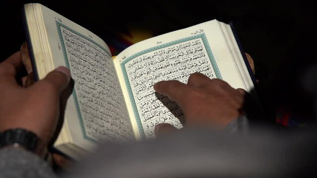 Reading Quran, Reading a Koran, Reading a Holy Quran with finger. Quranic reading. Reading a holy book. reading the Holy Qur'an, Reading in dark, Slowmotion Footage.