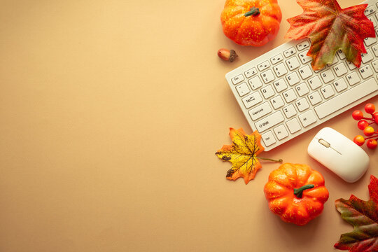 Autumn office workspace. Keyboard, pumpkin with autumn leaves. Flat lay with copy space.