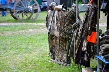 A close up on a display of camo jackets and other military items of apparel seen on a small stand or stall during a military picnic organized in summer in Poland