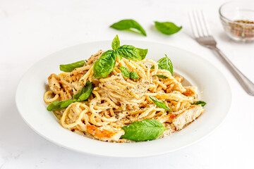 Creamy Spaghetti Pasta with Chicken on a White Dish Garnished with Fresh Basil Leaves, Close Up Pasta Photo on White Background

