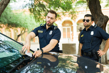Caucasian police agents leaving a parking fine in a car