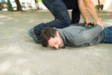 Young man criminal getting arrested lying on the floor