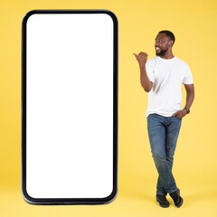 African Man Near Big Cellphone Pointing At Screen, Yellow Background