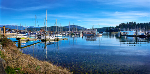 Gibsons Harbour. Yachts, boats at the piers against the backdrop of mountains in sunny weather. Gibsons, Sunshine Coast, BC, Canada - obrazy, fototapety, plakaty