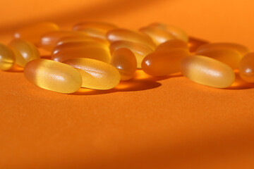 Dietary supplementation. omega-3 fish fat oil capsules. Orange background.