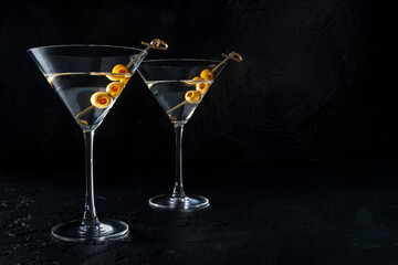 Martini, two glasses with spicy olives, on a black background. Alcoholic drinks with a place for text