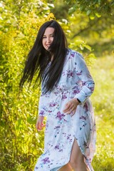 Happy dark hair woman of plus size at nature enjoying life. Young lady with excess weight, stylishly dressed at the city park .Natural beauty