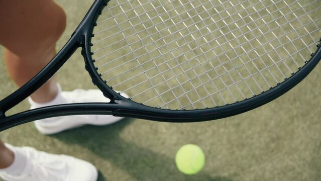 4k video Unrecognizable young woman in white on tennis grass court bouncing the ball before serving. Female playing tennis on sunny day. Tennis club concept.