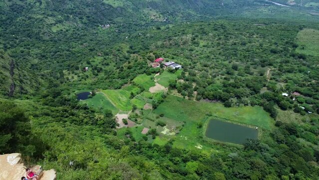 Drone aerial view of Mirador Salto del Mico, overhanging rock in the Colobian Andes in Barichara  a town in northern Colombia South America  - lonely man traveler sitting overhanging the rock