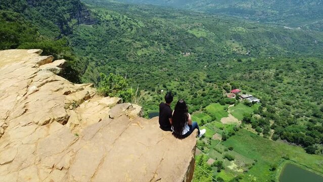 Drone aerial view of Mirador Salto del Mico, overhanging rock in the Colobian Andes in Barichara  a town in northern Colombia South America  - couple of lovers sitting overhanging the rock