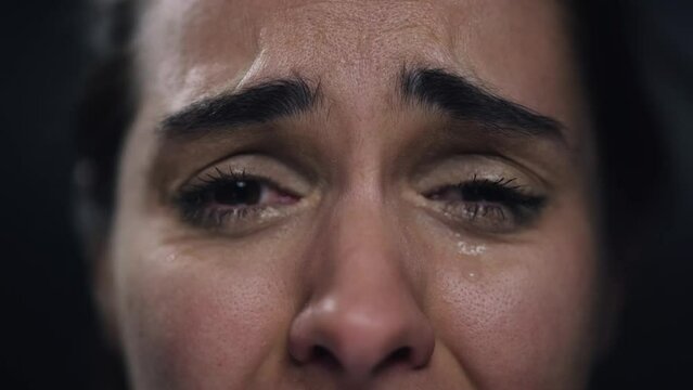 Video of young woman close-up crying on black background. Mental illness concept.