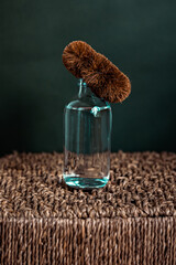 Glass bottle and washing brush on a wicker stand. Sustainable lifestyle