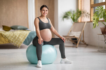 Beautiful Pregnant Woman With Big Belly Sitting On Fitness Ball At Home