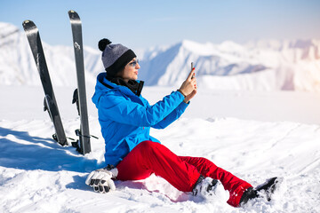 Fototapeta na wymiar Woman skiing in the mountains and talking on the phone