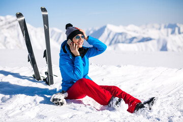 Woman skiing in the mountains and talking on the phone