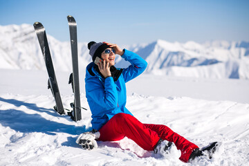 Fototapeta na wymiar Woman skiing in the mountains and talking on the phone