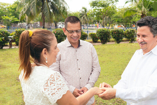 Mature couple getting married by priest during sunny day