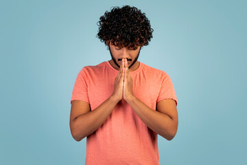 Eastern young man holding hands by his mouth, praying