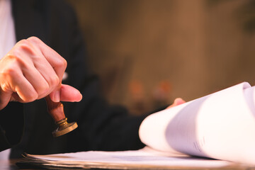 close-up of person stamping documents to approve agreements,