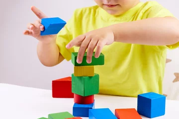 Fototapete Lego A child plays with playful colored geometric shapes on a light table. The child builds towers from toy building bricks. selective focus  © Наталья Дорожкина
