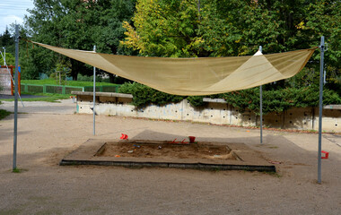 Fototapeta premium there is a tarpaulin between two wooden pillars. roof serving as a shading for the sandpit or terrace at the house or restaurant in the front garden and in the park. metal wires and cords