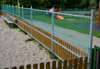 fencing of the children's playground with an additional net above the wooden fence. the galvanized...