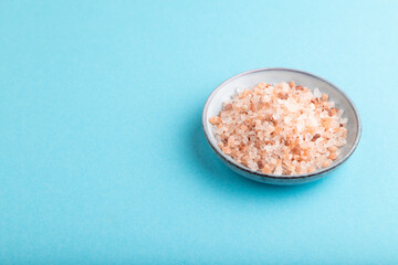 plate with pink Himalayan salt on blue pastel. side view, copy space.