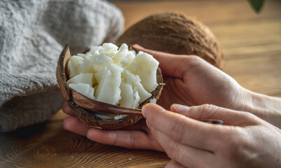 Hands of woman hold a bowl with fresh coconut oil and a wooden spoon. Concept of a healthy ingredient for cooking and natural cosmetics