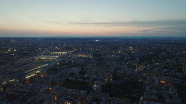 Aerial panoramic view of evening city and colour twilight sky in background. Richly illuminated central train station. Rome, Italy