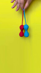 Sex toys. Red and blue geisha balls on a hand. Yellow background. Useful for sex shop, adult