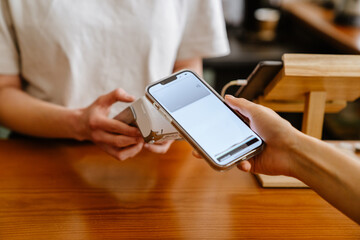 Blonde white barista woman working with terminal in cafe