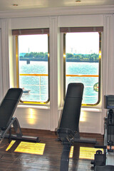 Moderne Fitnessgeräte mit roter Lederbespannung in Sportstudio auf Kreuzfahrtschiff - Modern...
